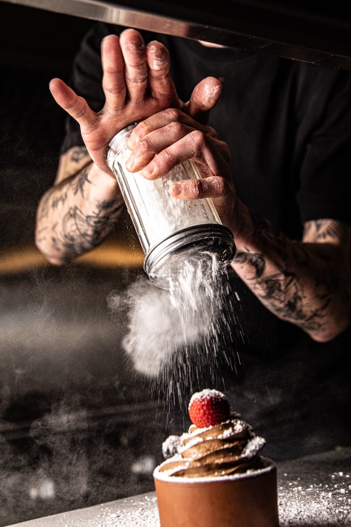 Le chef saupoudre un dessert de sucre glace